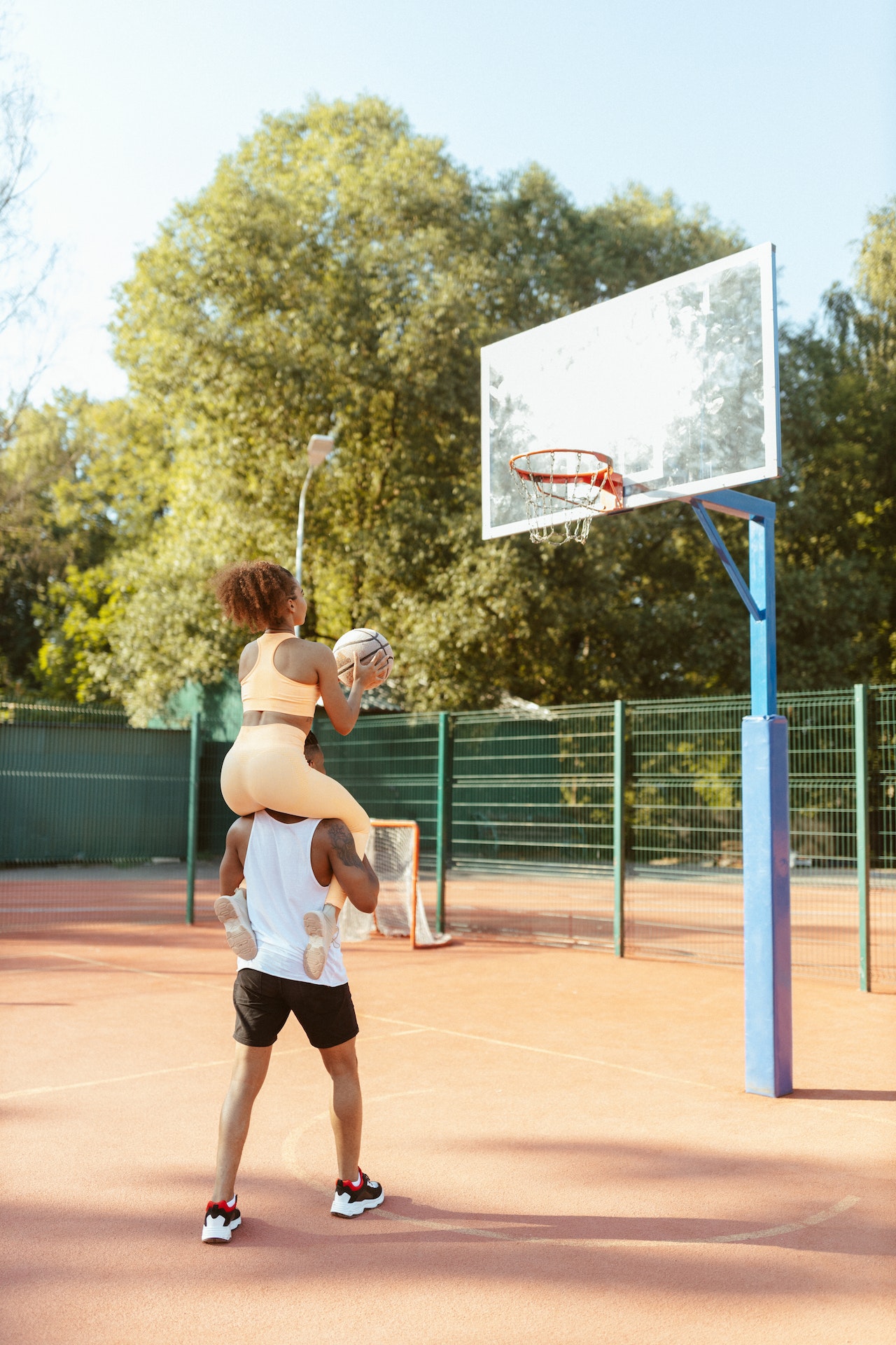 A teen couple playing basketball for a date