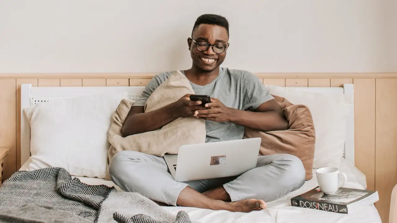 Man Sitting on Bed While Playing Texting Games Man Sitting on Bed While Playing Texting Games
