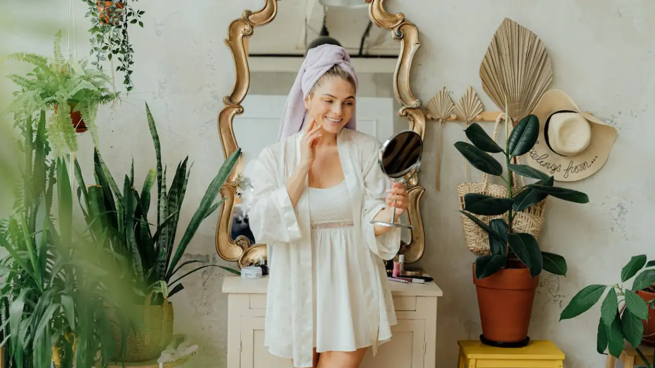 Woman in white Bathrobe looking at a mirror touching her face after using a best powder cleaner