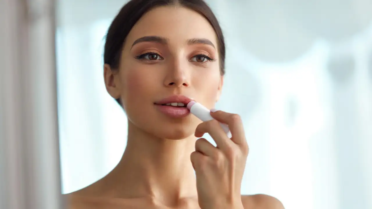 A woman using one of the Best Tasting Lip Balms for a Kissable Pout